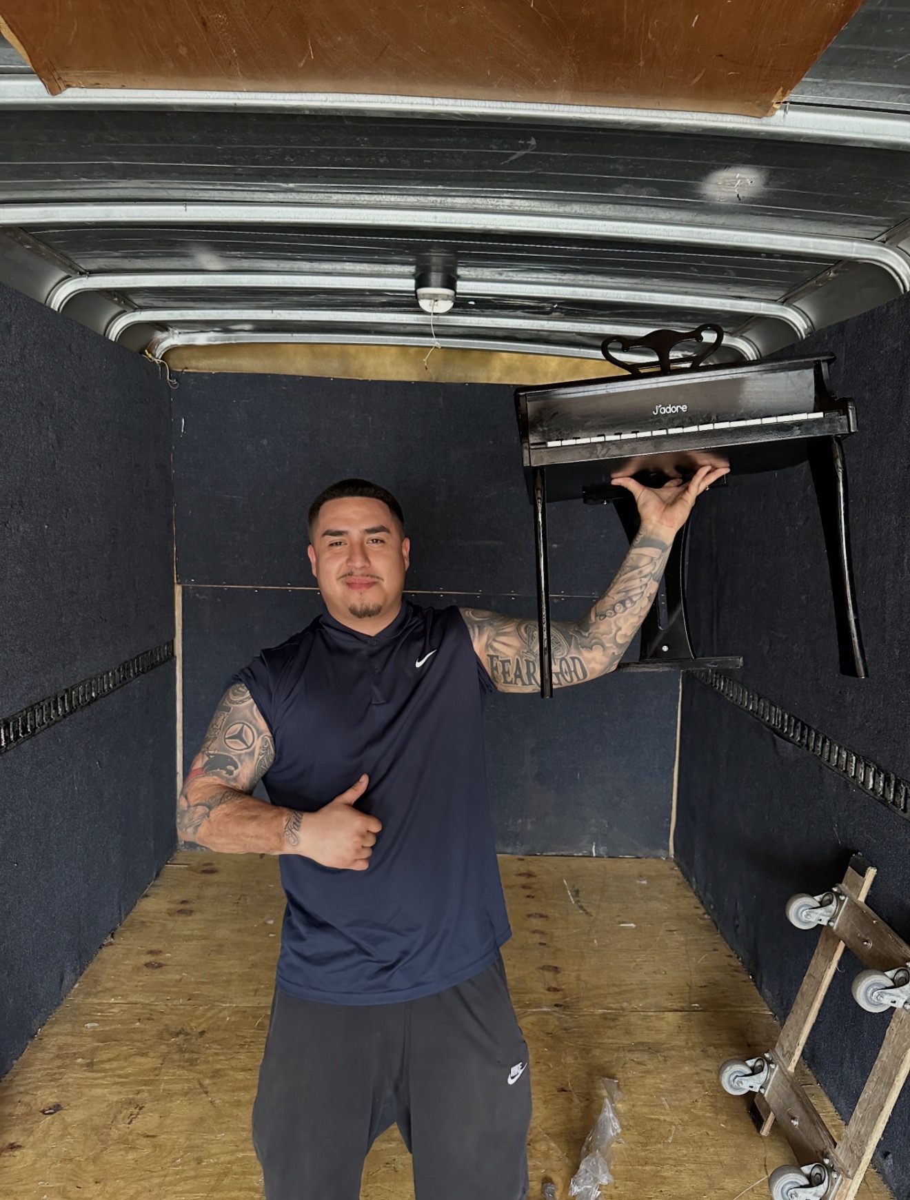 Gio securing a small piano inside a padded moving truck